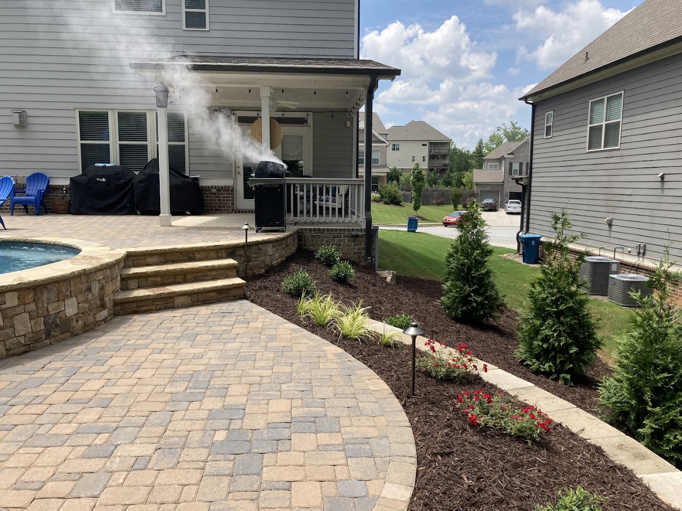 Google Maps review photo showing poolside pavers, stone steps, planting beds, and path-light fixtures