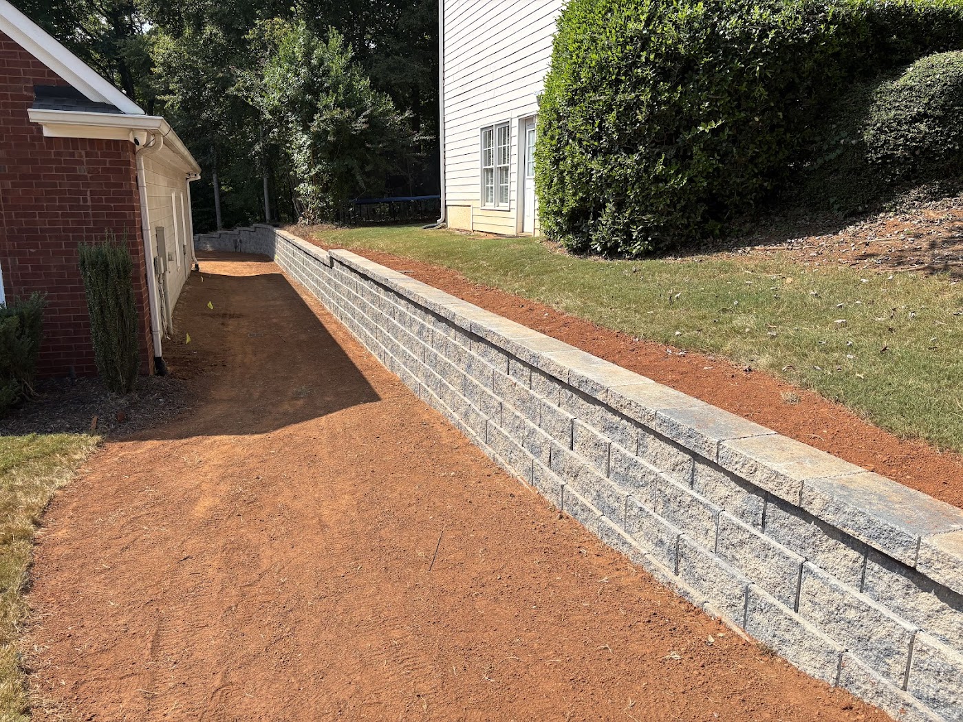 Google Maps review photo showing long retaining wall, grading, sod edge, and clean bed line